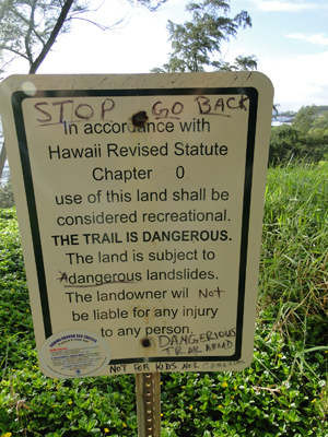 Picture of the warning sign on the trail to the Red Sand Beach near Hana on the island of Maui, Hawaii.